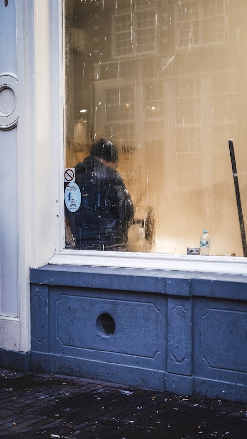 Man in Jacket Standing behind Window