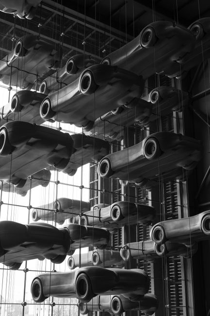 Captivating black and white art installation of car models hanging in a modern industrial space.