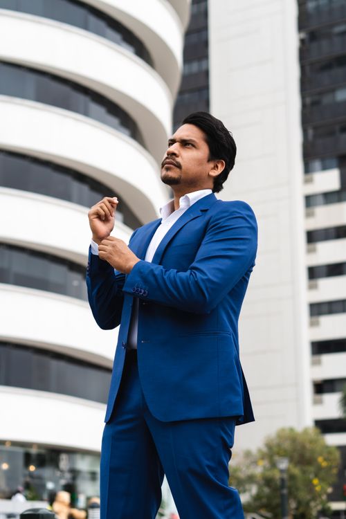 Free Confident businessman in a blue suit posing against modern Guayaquil architecture. Stock Photo