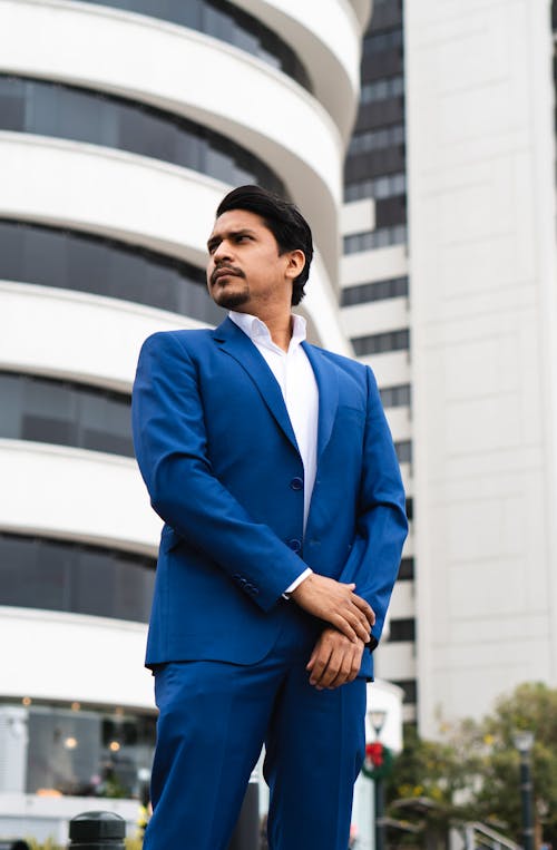 Elegant Man in a Blue Suit Standing on the Background of Modern Buildings in City 