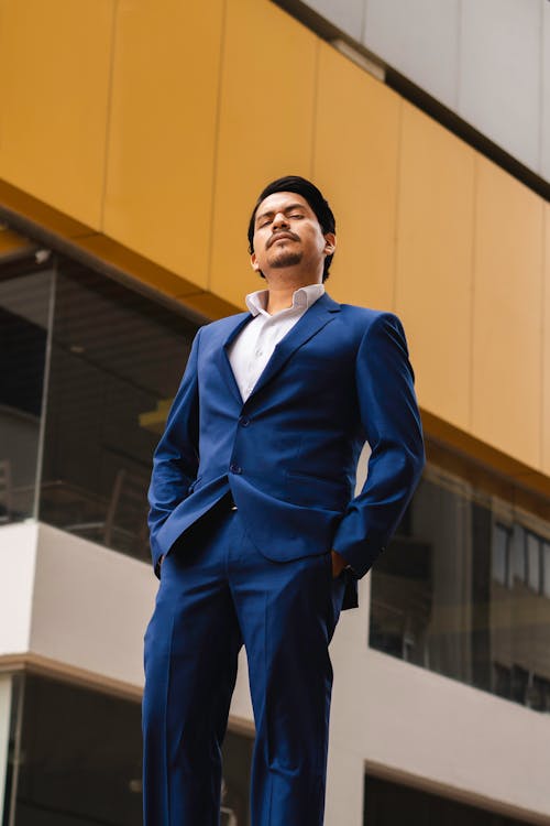 Low Angle Shot of a Man in a Blue Suit Standing on the Background of a Building 
