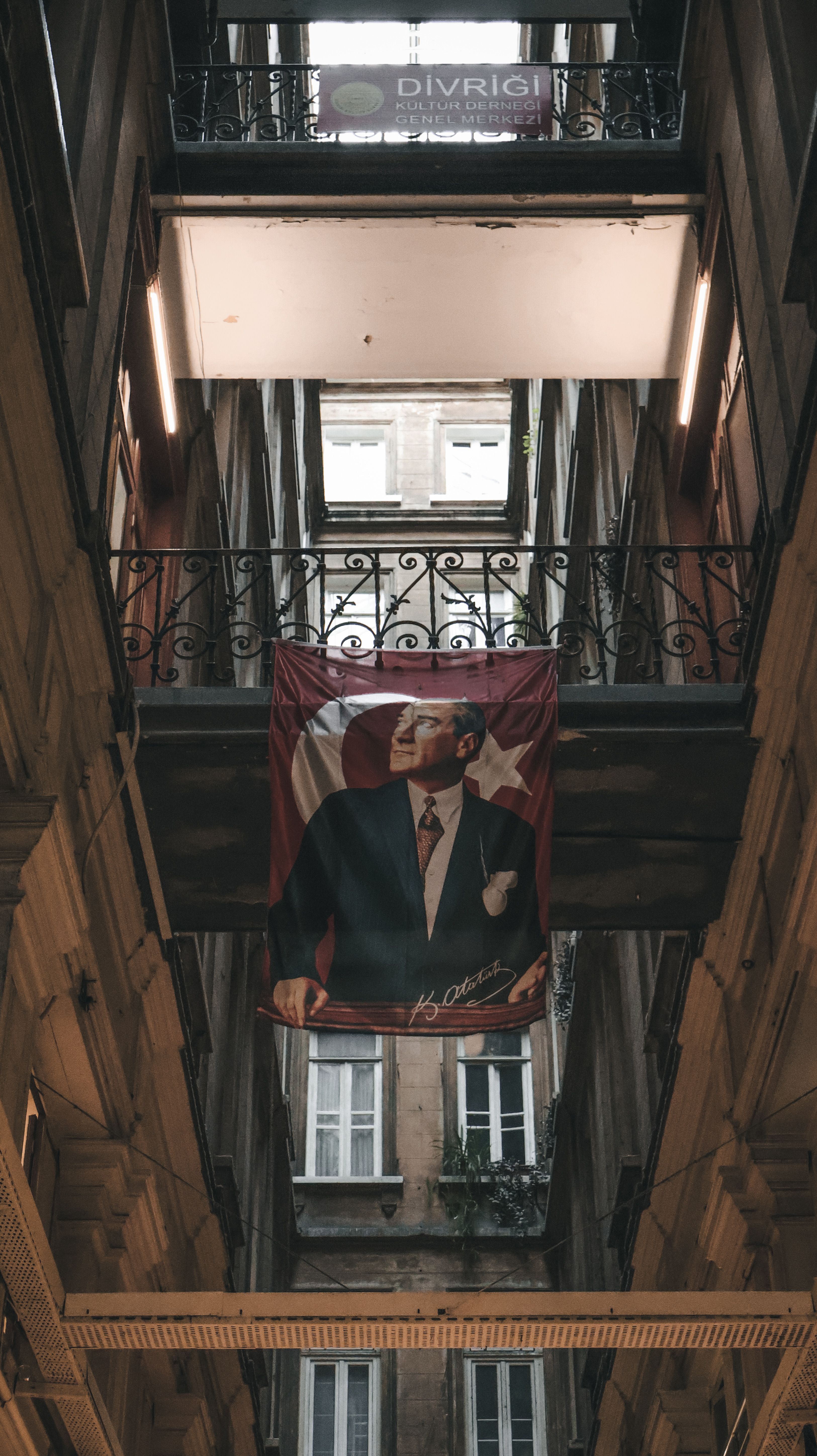 Low angle view of an urban building with Atatürk banner and railings.