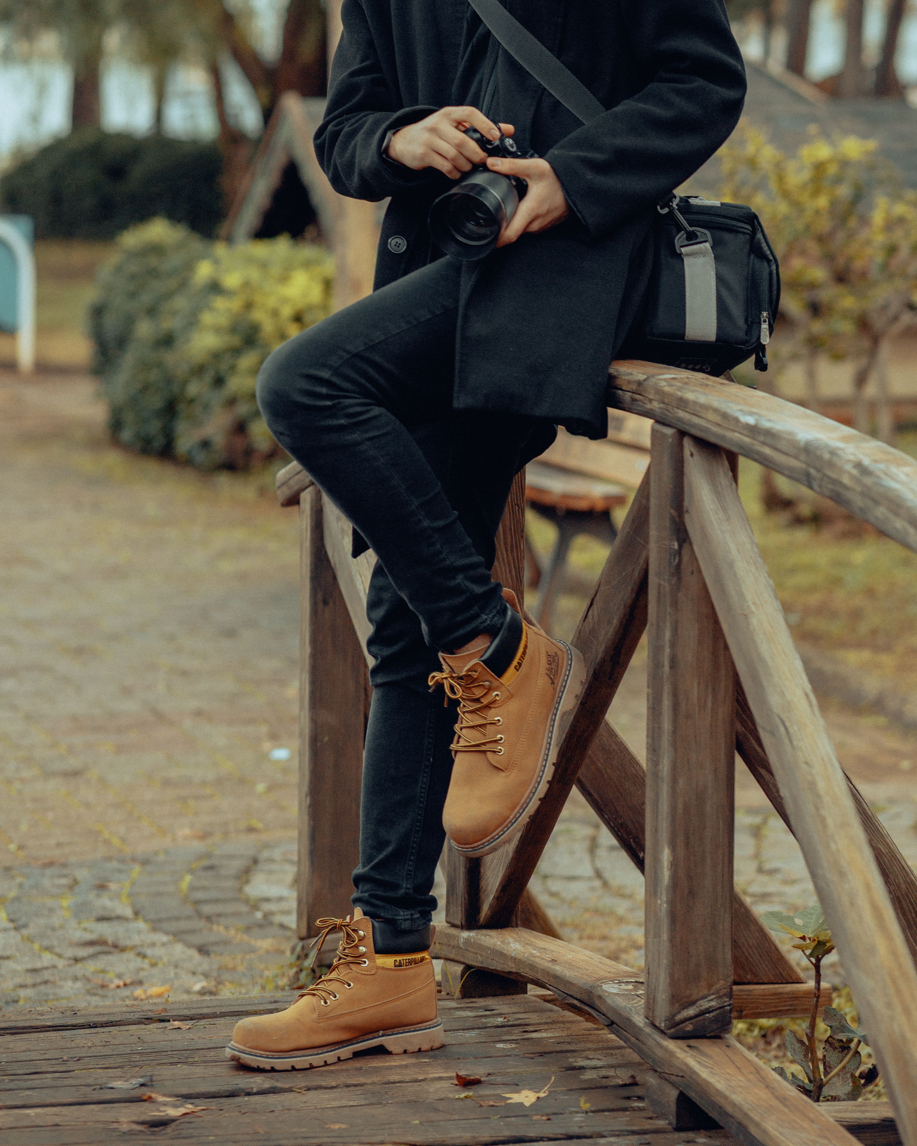 Man with Camera Leaning on Wooden Railing · Free Stock Photo