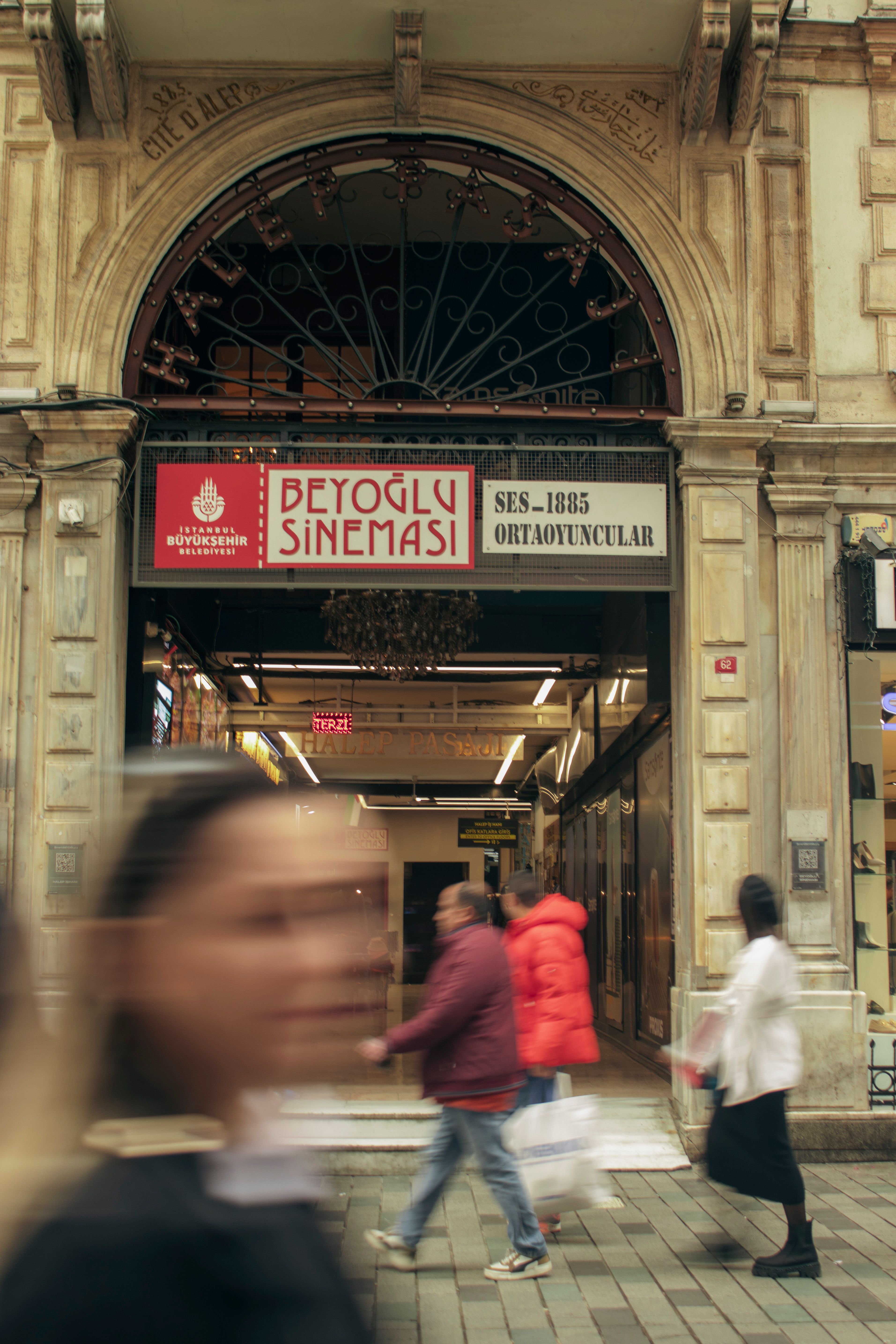Blurred pedestrians pass historic Beyoglu Sinemasi in Istanbul, Turkey, capturing urban life.