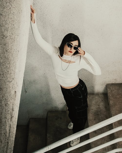 Model in a White Blouse and Black Cargo Pants with White Seams on the Staircase
