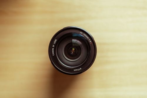 Free Top view of Canon camera lens on a wooden surface in a flat lay arrangement. Stock Photo