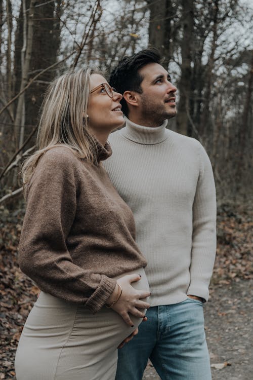 Photo of a Pregnant Woman Standing with a Man in a Forest