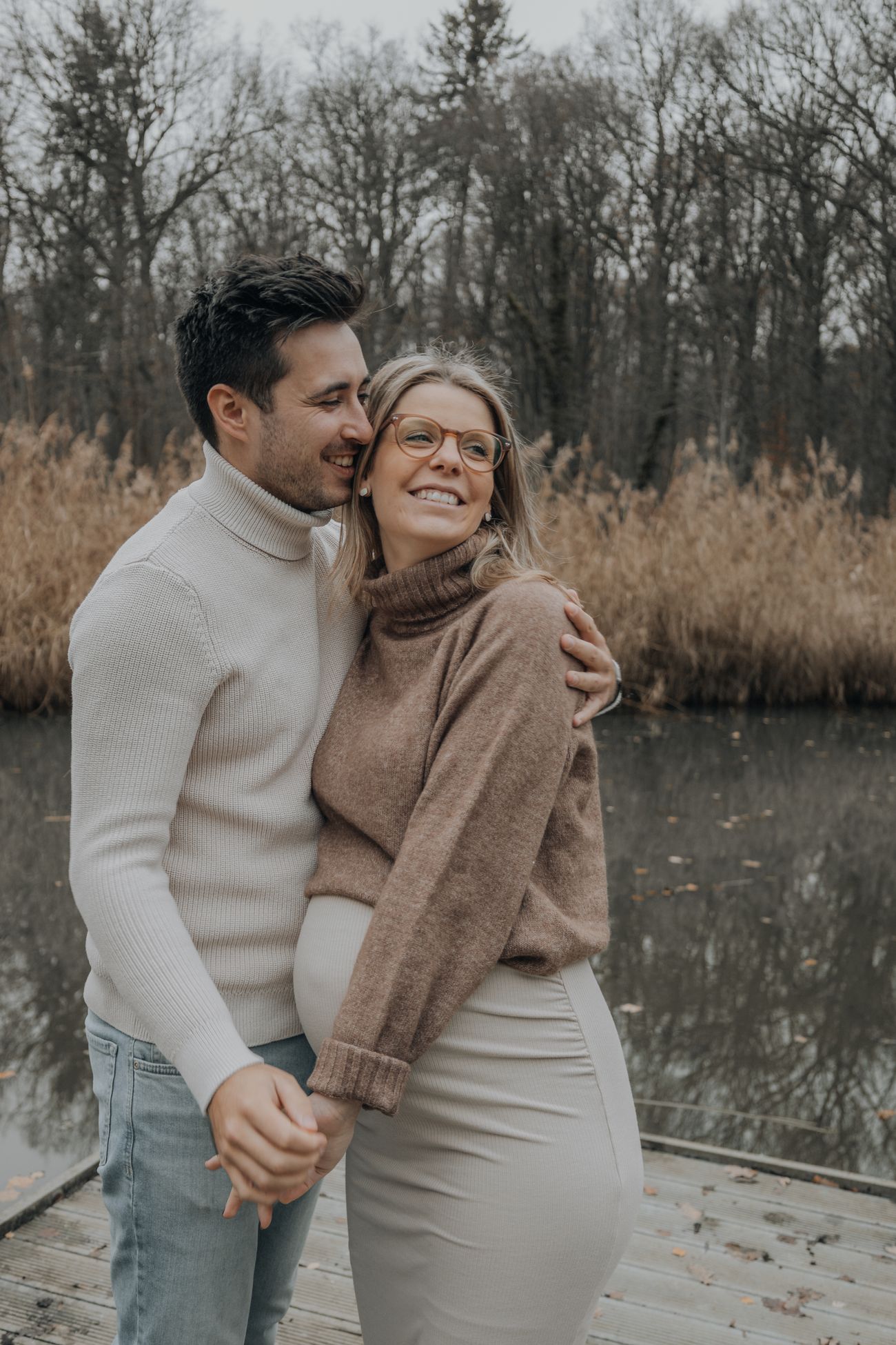 Casal sorrindo e abraçado esperando um bebê