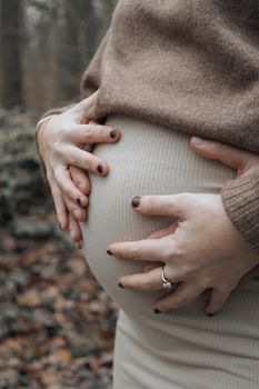 Expectant couple gently holding the pregnant belly in a serene outdoor setting. - Fotografer Sidoarjo