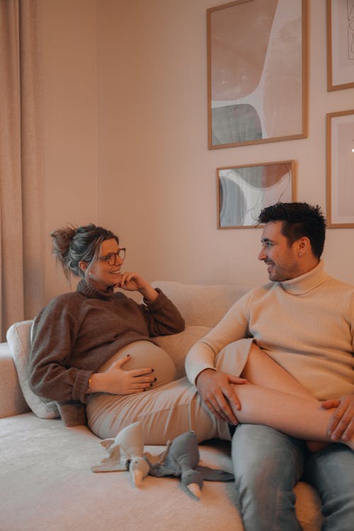 Pregnant Woman Sitting with Her Partner on a Sofa