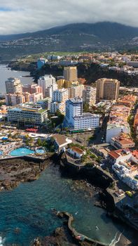 Scenic aerial shot of coastal Puerto de la Cruz, Tenerife with lush mountains in the backdrop.