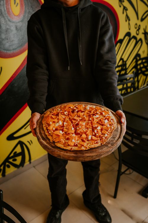 Free Man presenting a mouth-watering pizza in a trendy urban pizzeria, perfect for food-themed stock photos. Stock Photo