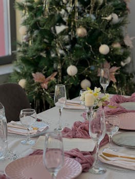 Festive table setting with wineglasses and a decorated Christmas tree in the background.