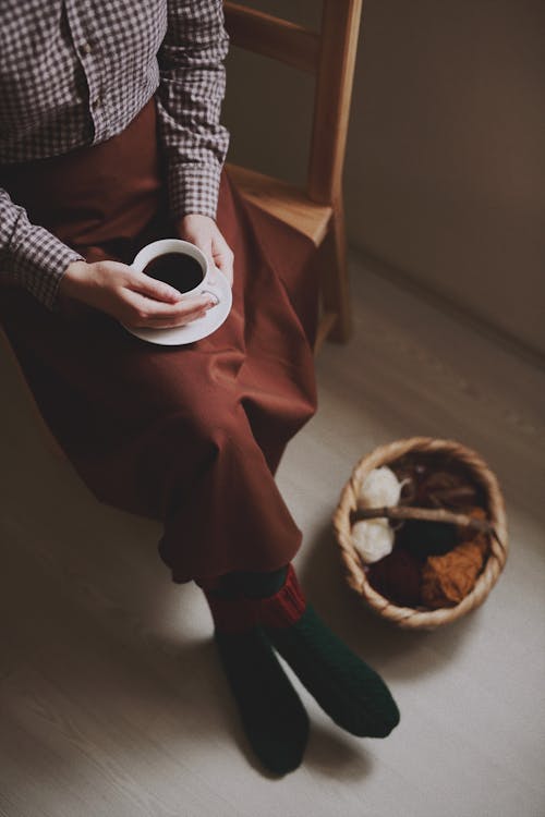 Woman Sitting on a Wooden Chair and Drinking a Cup of Coffee 