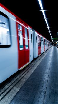 Dynamic subway train moving fast in an underground station with motion blur.