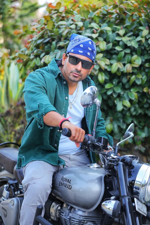 Man in a Bandana and Sunglasses Sitting on a Royal Enfield Bullet Motorcycle 
