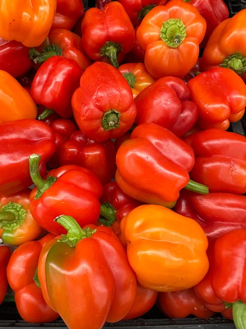 Free A stack of fresh red and orange bell peppers showcasing vibrant colors and freshness. Stock Photo
