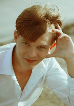 Portrait of a young redhead man smiling outdoors wearing a white shirt.