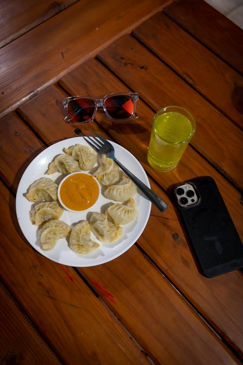 Traditional Momo Dumplings, a Drink, Sunglasses and a Smartphone Lying on a Table 