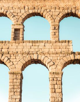 Close-up of the ancient Roman stone arches of the Segovia Aqueduct against the sky.
