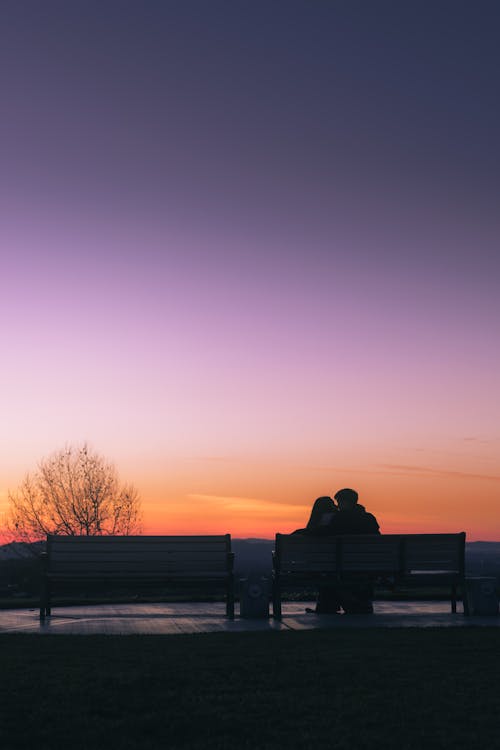 Young Couple Kissing on a Bench at Dusk