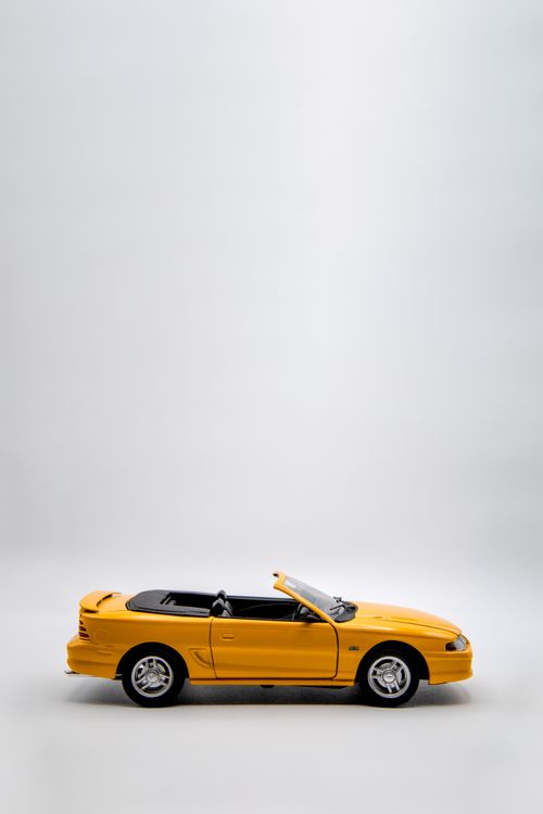 Free Close-up of a vibrant yellow model toy convertible on a white background Stock Photo