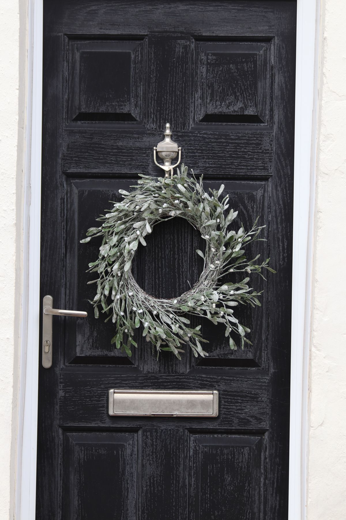 Stylish black wooden door with a winter wreath, creating a festive entrance. Stock Photo.