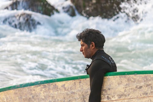 Man with a Surfboard Under His Arm Entering the Sea