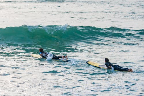 Tourists Swimming on Paddleboards Towards the Wave