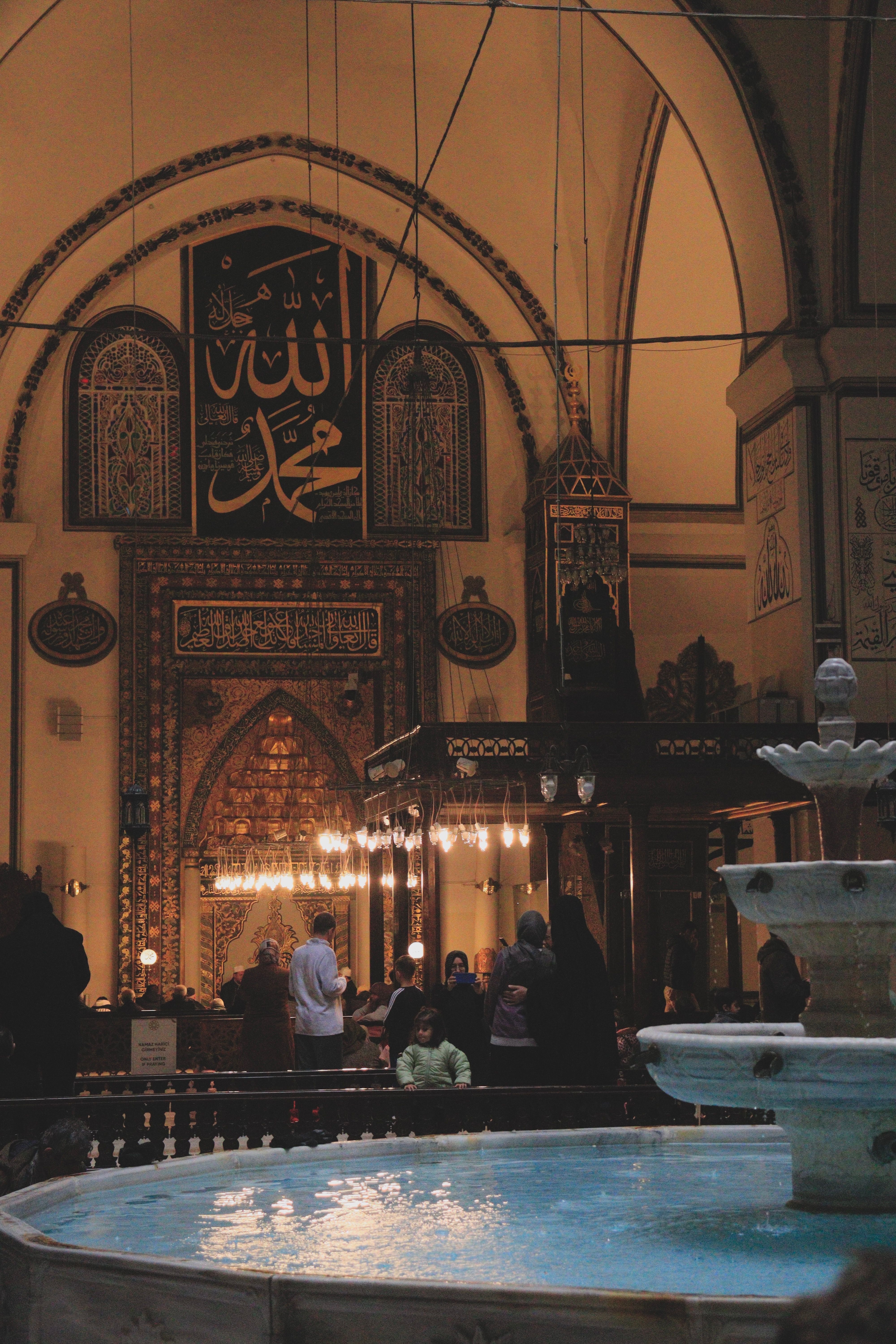 Beautiful interior view of a mosque with intricate designs and a central fountain, capturing a moment of reverence.