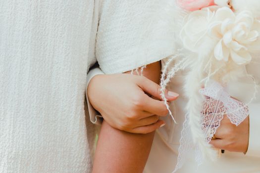Intimate close-up of a couple holding hands with a decorative bouquet.