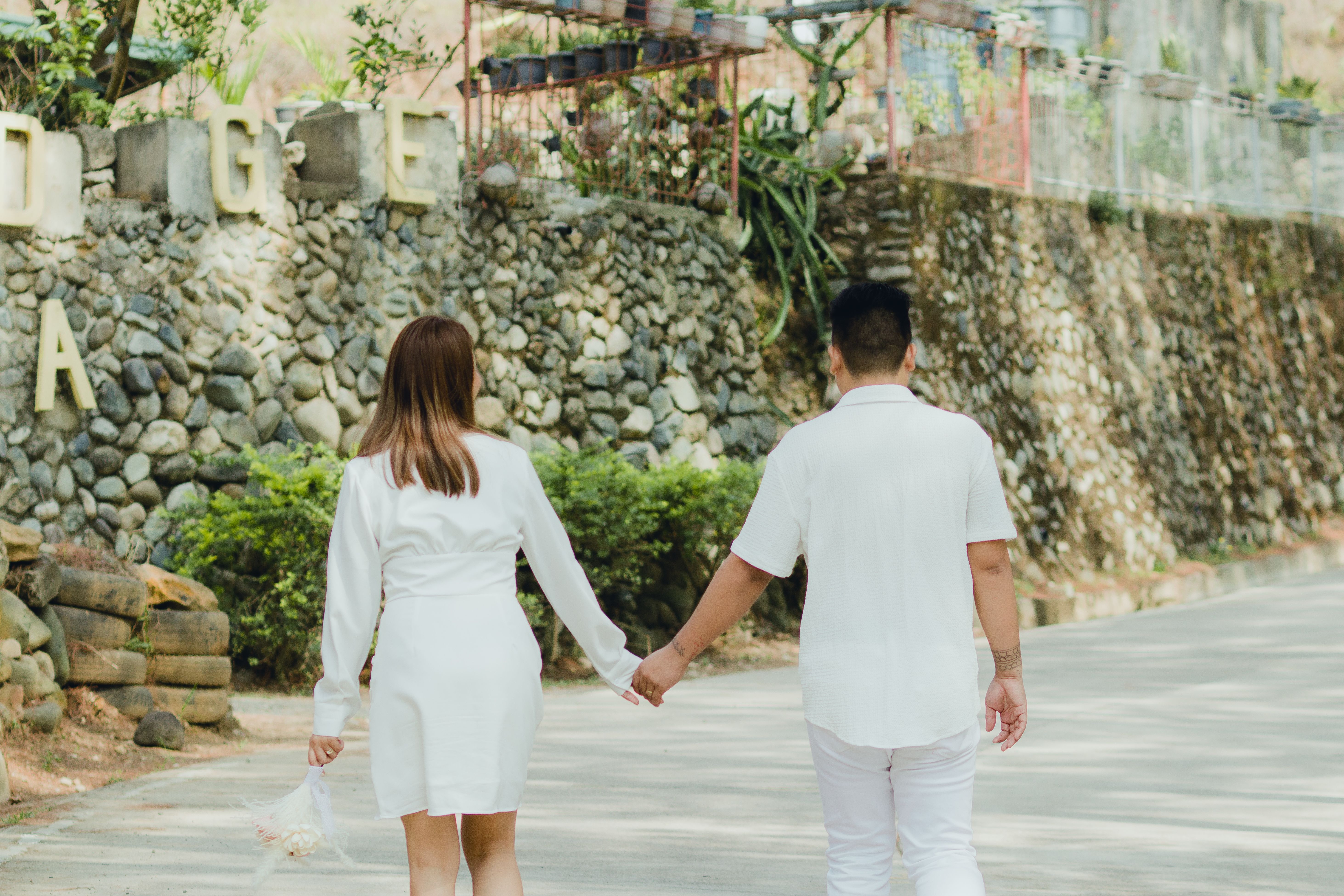 Back View of a Couple Holding Hands while Walking on a Pavement · Free ...