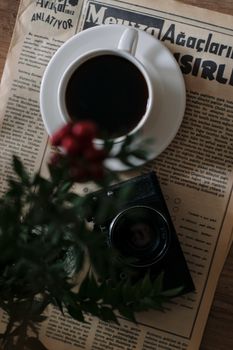 Top view of coffee cup, vintage camera, and newspaper with flowers.