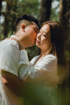 Young Asian couple embracing in a serene forest setting, depicting love and connection.