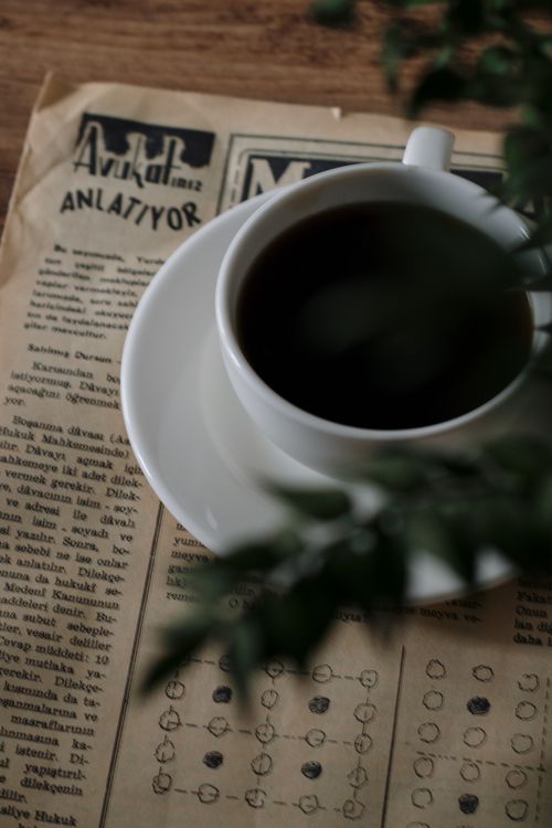 Free A warm cup of black coffee on a vintage newspaper with greenery. Stock Photo