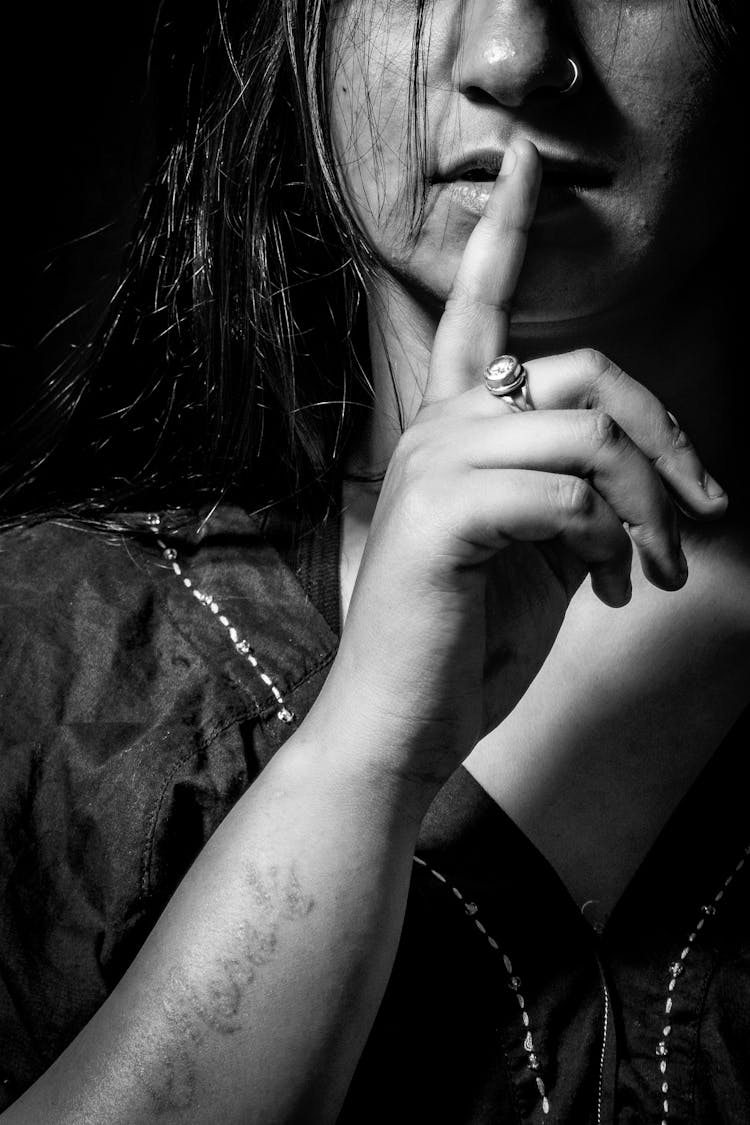 Black And White Closeup Photo Of A Woman With A Finger On Her Lips