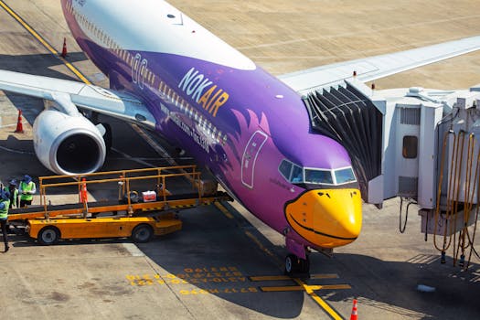 Nok Air airplane docked at an airport gate with vibrant livery and ground crew.