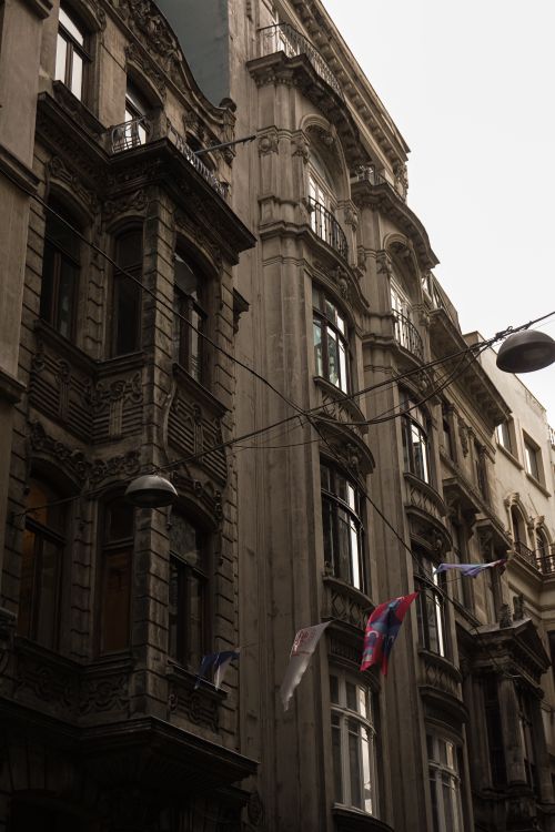 Free A vertical shot of ornate city facades showcasing intricate urban architectural details on a cloudy day. Stock Photo