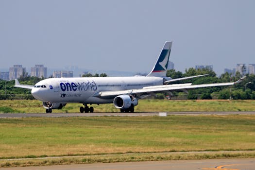 Cathay Pacific aircraft with oneworld livery on runway, ready for takeoff at airport.