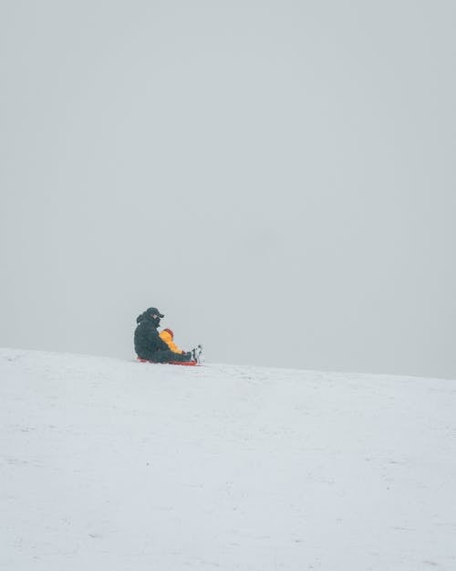 Parent Sitting with Child on Sleigh in Snow