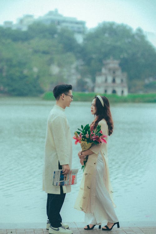 Young Couple in Traditional Clothing Standing by the Lake in a Park 