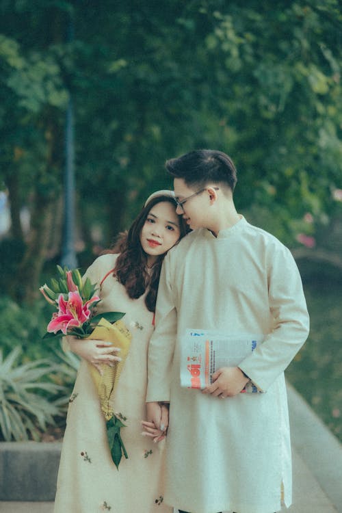 A Couple in Traditional Clothing Holding Hands and Hugging Outside 