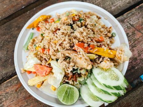 A vibrant plate of vegetable fried rice garnished with fresh cucumber slices and lime, perfect for a healthy meal.