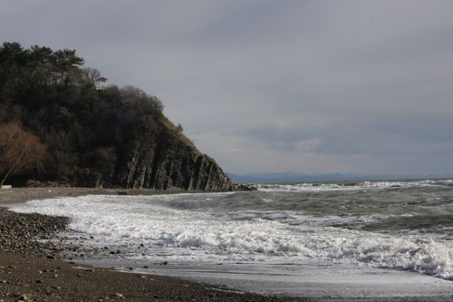 Free Rocky coastline with waves crashing against a cliff under a cloudy sky. Stock Photo