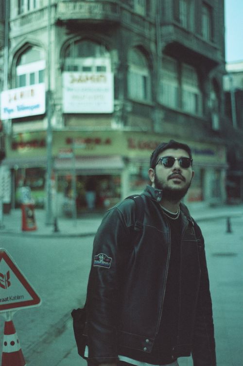 Free Stylish man with sunglasses and jacket walking on an urban street in Istanbul, Türkiye. Stock Photo