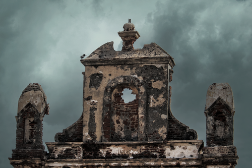 Free Weathered ruins of an old church facade set against a moody stormy sky. Stock Photo