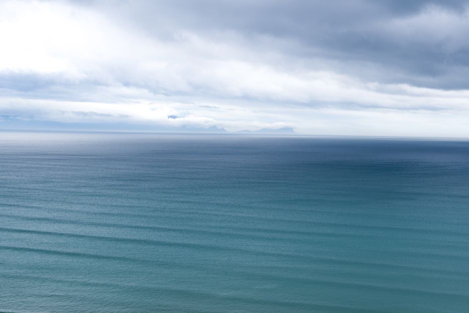 Peaceful ocean landscape in Cape Town with cloudy sky and gentle waves, creating a tranquil scene.