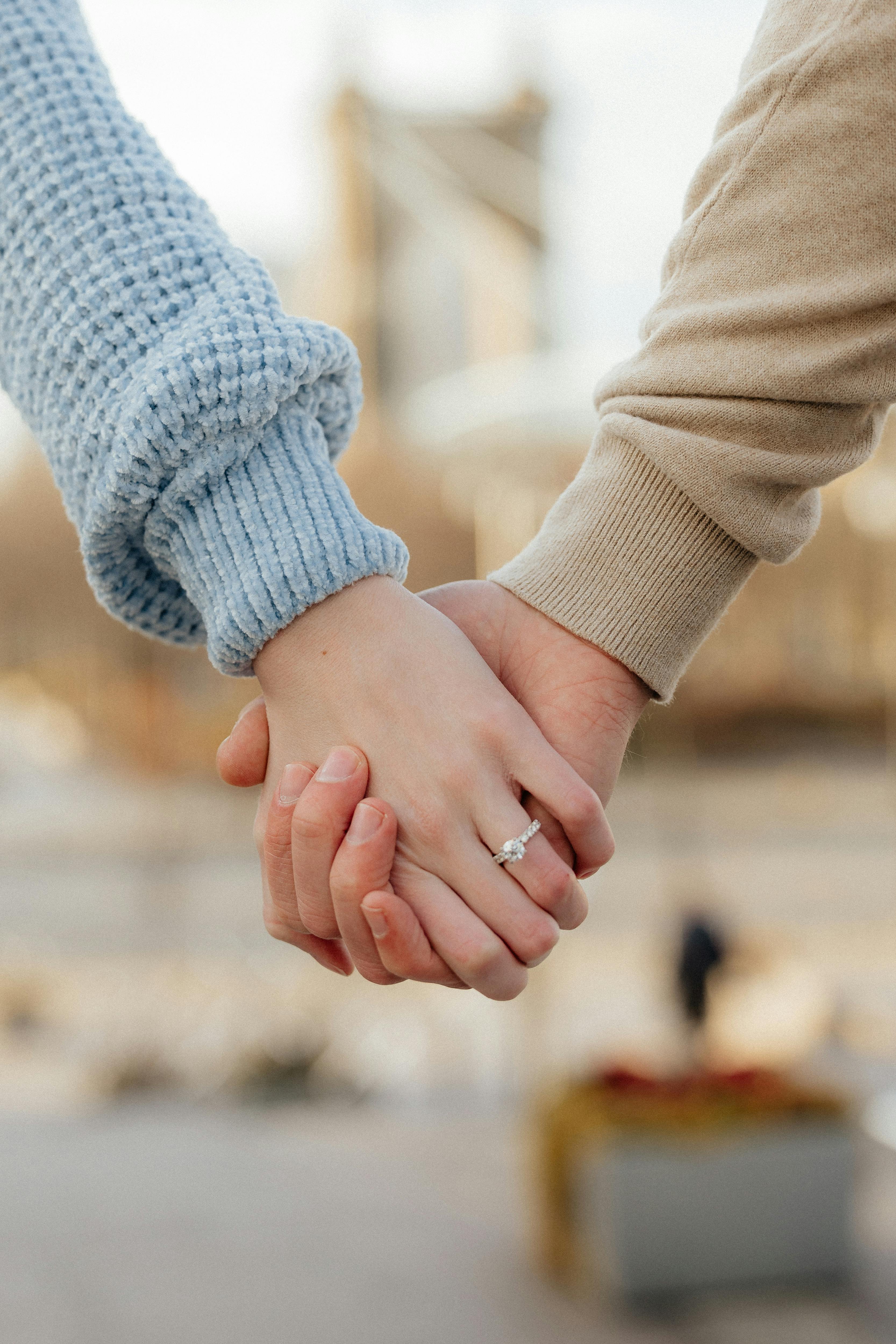 A couple holding hands with a visible engagement ring in Cincinnati, Ohio.