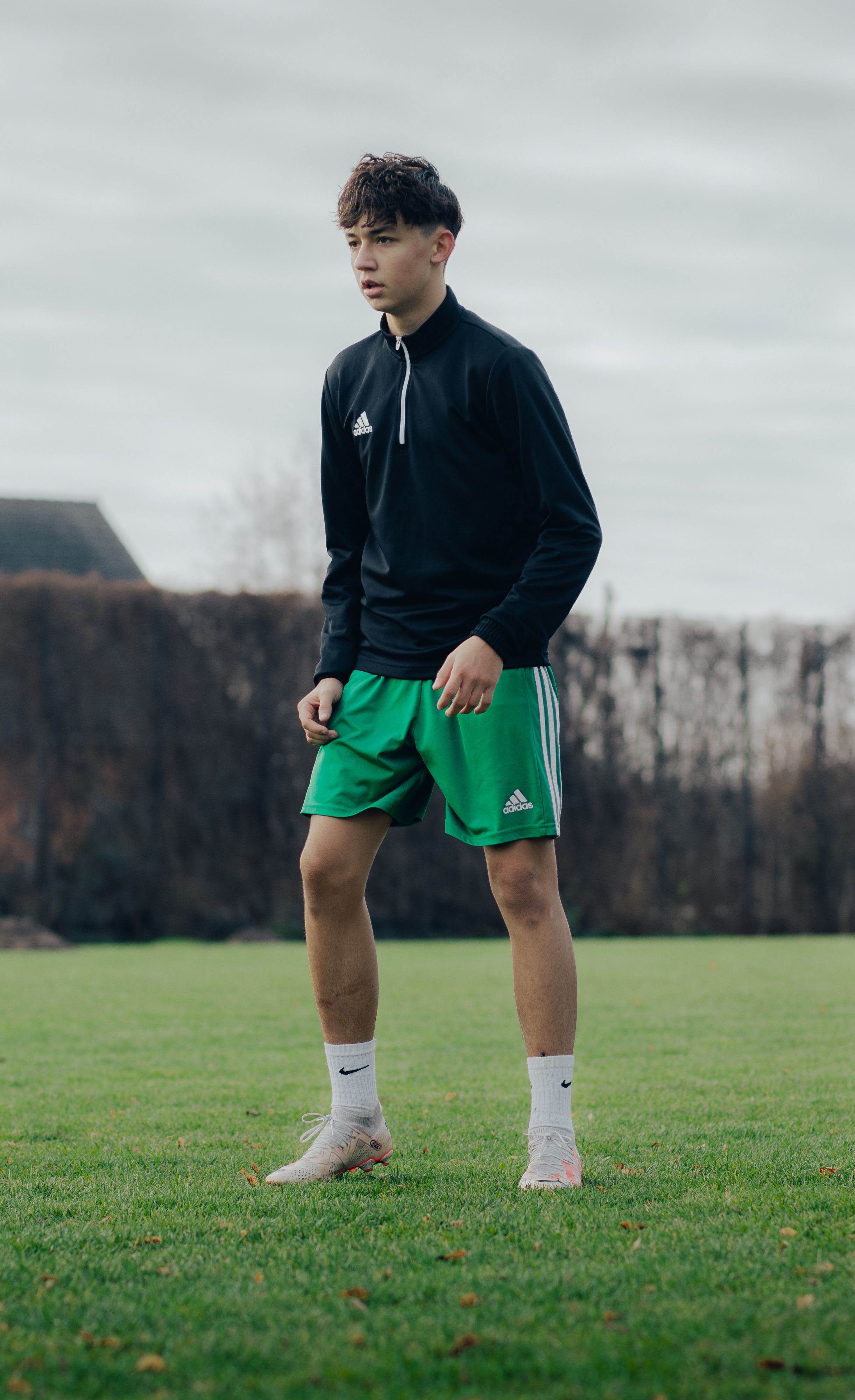 Teenage boy in sportswear practicing soccer on an outdoor field in Berlin.
