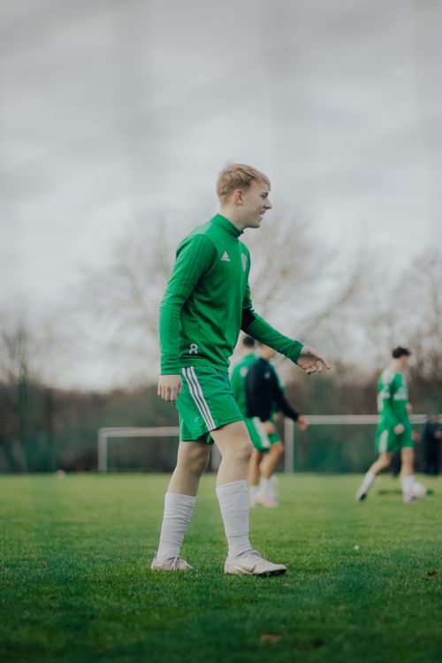 Free Teen male soccer players in green sportswear on a grass field in Berlin, enjoying a game. Stock Photo